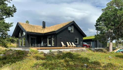 a small black house with chairs on a hill at Large Cabin Near Hardangervidda With Sunny Veranda in Veggli