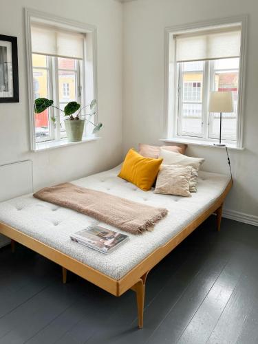 a bed sitting in a room with two windows at Live In Classic Skagen House In Skagen's Heart in Skagen