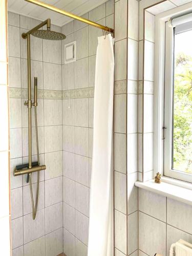 a shower with a white shower curtain in a bathroom at Idyllic House With Cliff Formations And Ocean View in Sandvig