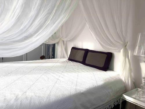 a bedroom with a white bed with white curtains at Idyllic House With Cliff Formations And Ocean View in Sandvig