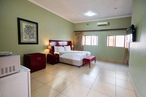 a bedroom with a bed and a tv in it at Tamboti Guest Lodge in Pretoria