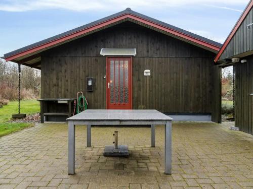 a picnic table in front of a building with a red door at Charming Wooden Summer House In Trend in Løgsted