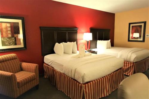 a hotel room with two beds and a chair at Hotel DSR Tark Plaza Near IGI Airport Delhi in New Delhi
