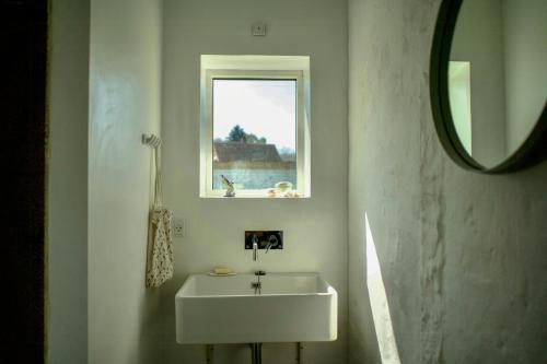 a bathroom with a white sink and a window at Former Railway Workers House By Kragenæs Harbour in Torrig