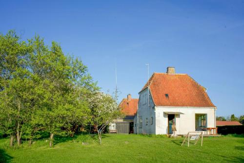 a white house with a red roof in a field at Former Railway Workers House By Kragenæs Harbour in Torrig