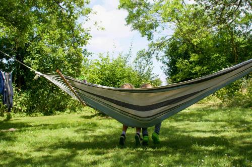 two people sitting in a hammock in a field at Former Railway Workers House By Kragenæs Harbour in Torrig
