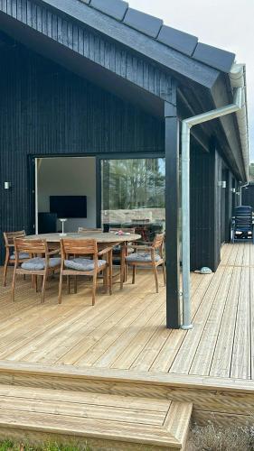 a wooden deck with a table and chairs on it at Modern Holiday Home Near Vesterløkken Beach in Tanderup
