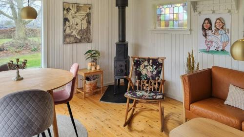 a living room with a wood stove and a table and chairs at Holiday Home Idyll By Roskilde Fjord in Kirke-Hyllinge