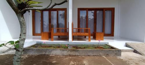 a bench sitting in front of a house with flowers at Nêst Guesthouse Tetebatu in Tetebatu