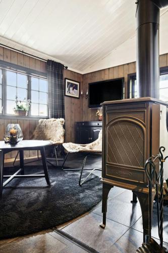 a living room with a fireplace and a table at Cosy Cabin With Annex At Blefjell in Kongsberg