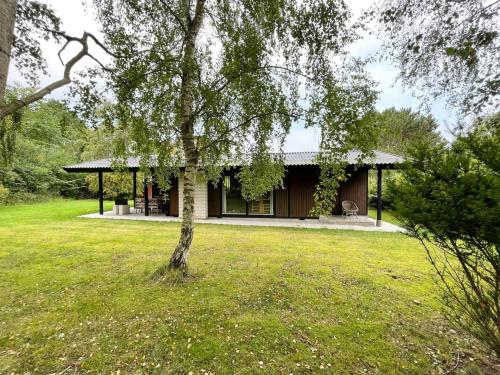 una casa con un árbol delante en Original 70S Home Surrounded By Woods, en Vejby