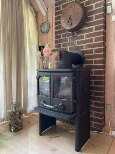 a stove in a room with a clock on a brick wall at Retro Idyll And Bird Sounds In Quiet Oasis in Asperup
