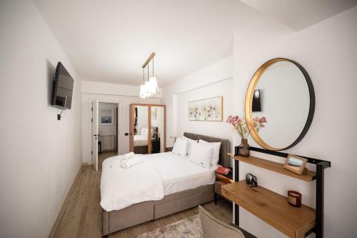 a bedroom with a large white bed and a mirror at Ambient in Infinity Pool & Spa Resort in Mamaia