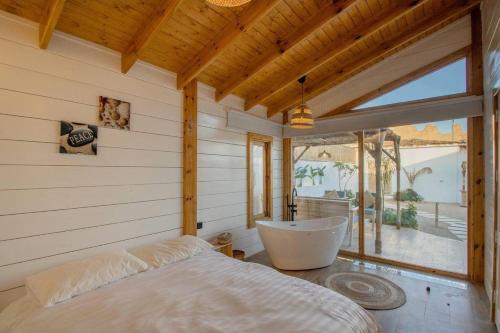 a bedroom with a tub and a large window at منتجع بامبو in Quşūr al Muqbil