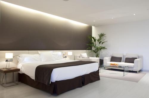 a bedroom with a large bed and a couch at Hotel Diagonal Plaza in Zaragoza
