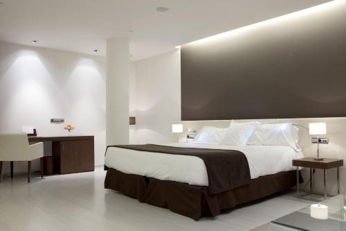 a bedroom with a large bed and two tables at Hotel Diagonal Plaza in Zaragoza