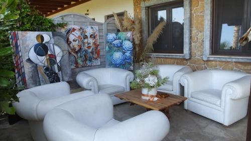 a living room with white couches and a table at Hotel Rurale Orti di Nora & SPA in Santa Margherita di Pula