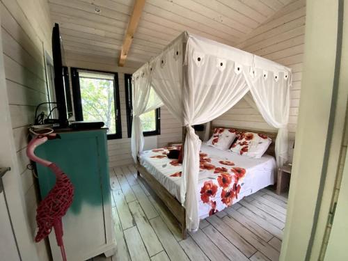 une chambre avec un lit à baldaquin dans l'établissement Chalet surplombant la pinède à 2Km de l'ocean, à Lacanau