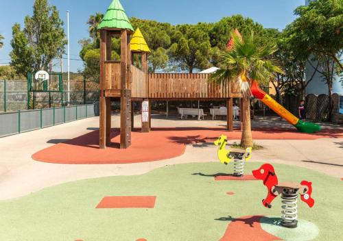 - une aire de jeux dans un parc avec un arbre et un toboggan dans l'établissement Camping Les Salins de la Gardiole - Eurocamp I Homair, à Vic-la-Gardiole