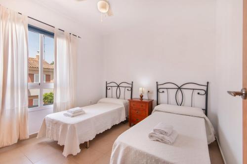 zwei Betten in einem weißen Zimmer mit Fenster in der Unterkunft Puerta Marina Costa de la Luz in La Redondela