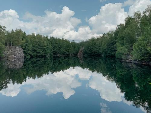 a river with a reflection of the clouds in the water at Restored Quarry House Near Nobel Laureate Home in Lönsboda