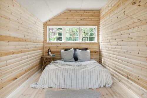 Un dormitorio con una cama en una pared de madera. en Rustic Vibe In 60S House By Roskilde Fjord, en Jægerspris