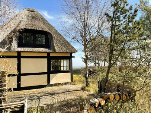 a building with a thatched roof with a bench in front at Timber House With View On Samsø in Nordby