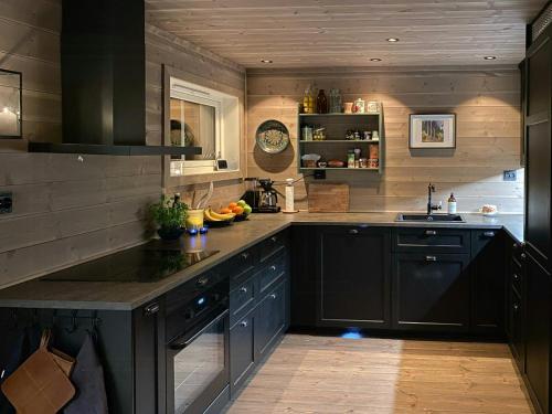 a large kitchen with black cabinets and a sink at Traditional Cabin With Views Of Hardangervidda in Uvdal