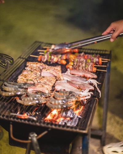 a group of meats and vegetables being grilled on a grill at Mafiya Resort in Koh Rong Island
