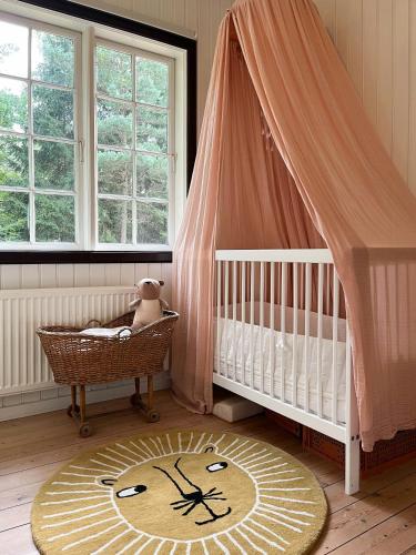 a baby room with a crib and a crib at Classic 30S House In Asserbos Woods in Frederiksværk
