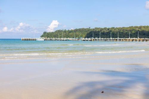 a sandy beach with a pier in the water at Mafiya Resort in Koh Rong Island