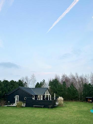 una casa negra con un banco en un campo en Family Holiday Home Near Denmark's Best Beach, en Væggerløse