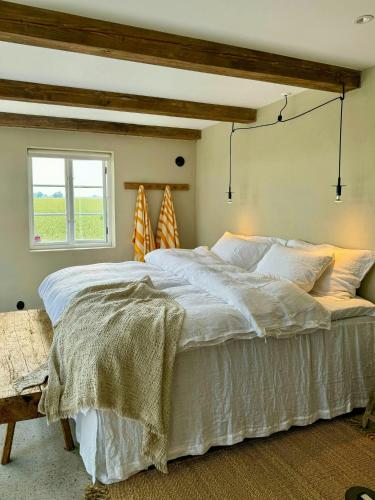 Un dormitorio con una gran cama blanca con ventana. en Traditional Farmhouse In The Heart Of Österlen, en Gärsnäs