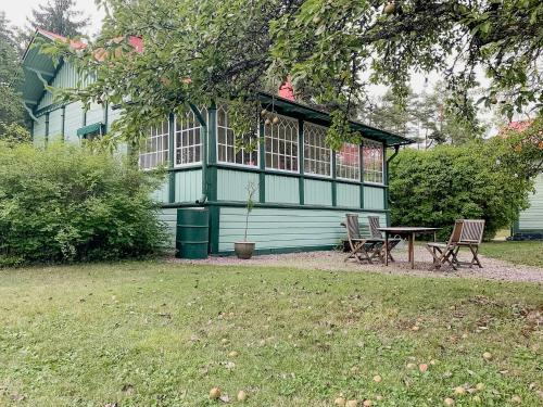 a green house with a table and chairs in a yard at Swiss-Style Villa With Forest Views Near Bråviken in Norrköping