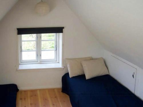 a attic bedroom with a bed and a window at Charming Farmhouse From 1875 Near Stevns Klint in Rødvig