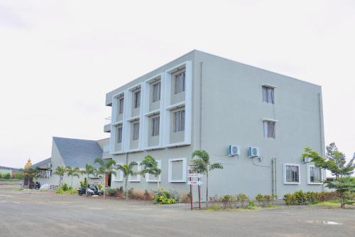 a large white building with palm trees in front of it at Hotel Laxmi Elite Karad in Karad