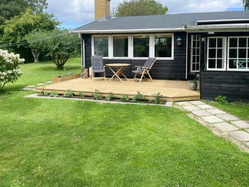 a house with a wooden deck in the yard at Cozy Summer Cottage On Picturesque Askø in Askø