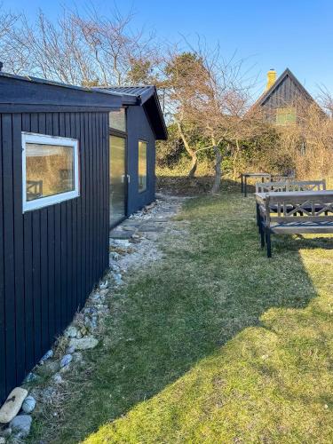 a black shed with a bench in a yard at Authentic Beach House In Ballen in Ballen