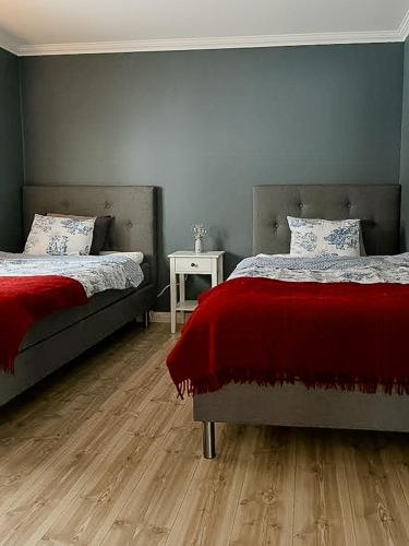 a bedroom with two beds with red blanket and a table at Nature Gem With Lake View Near Hudiksvall in Forsa