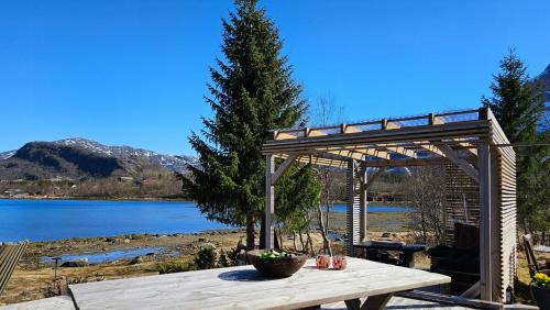 a wooden picnic table in front of a lake at Seaside Cabin With Panoramic Views In Oterstranda in Inndyr