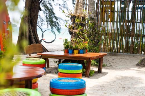 a table with colorful plates around it next to a bench at Mafiya Resort in Koh Rong Island