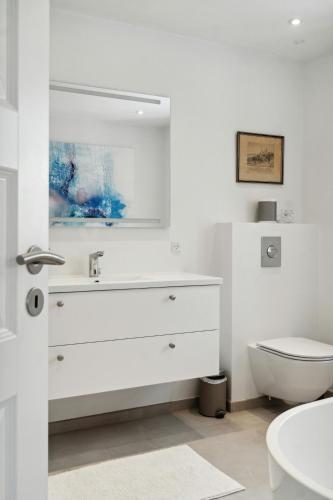 a white bathroom with a sink and a toilet at Enjoy Møn From Historic House in Stege