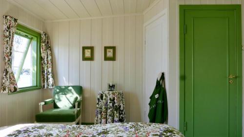 a bedroom with a bed and a green door and a chair at Cabin With Sunset Views And Private Dock in Sandefjord