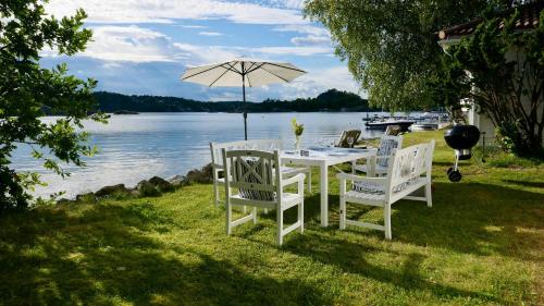 a table and chairs with an umbrella next to the water at Cabin With Sunset Views And Private Dock in Sandefjord