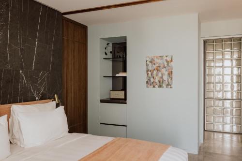 a bedroom with a white bed and a wall at Perianth Hotel, a Member of Design Hotels in Athens