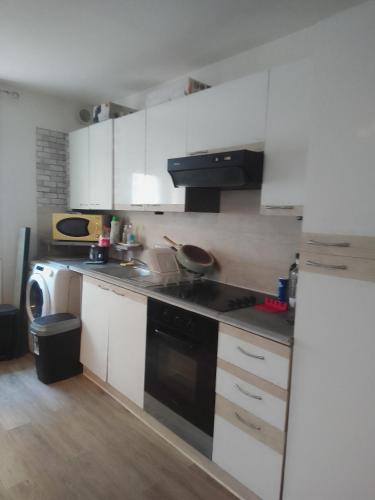 La cuisine est équipée de placards blancs et d'un four avec plaques de cuisson noires. dans l'établissement Spacieux studio entre mer et montagne, à Saint-Laurent-de-la-Salanque