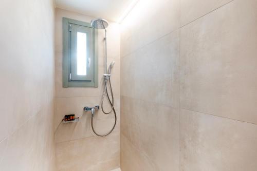 a bathroom with a shower with a mirror and a window at Olive Dryopis Apartments in Kithnos