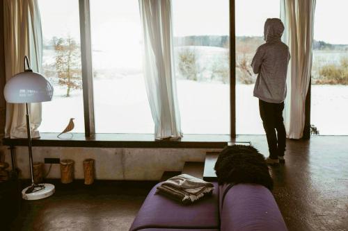 a person looking out of a large window at snow at Architect-Designed House With Views In Uckermark in Gerswalde