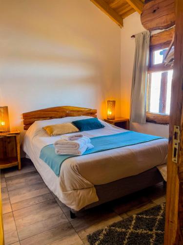 a bedroom with a bed with blue sheets and a window at Complejo Don Cirilo in Villa Pehuenia