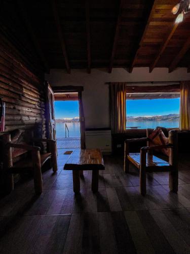 a living room with a table and a couch and two windows at Complejo Don Cirilo in Villa Pehuenia